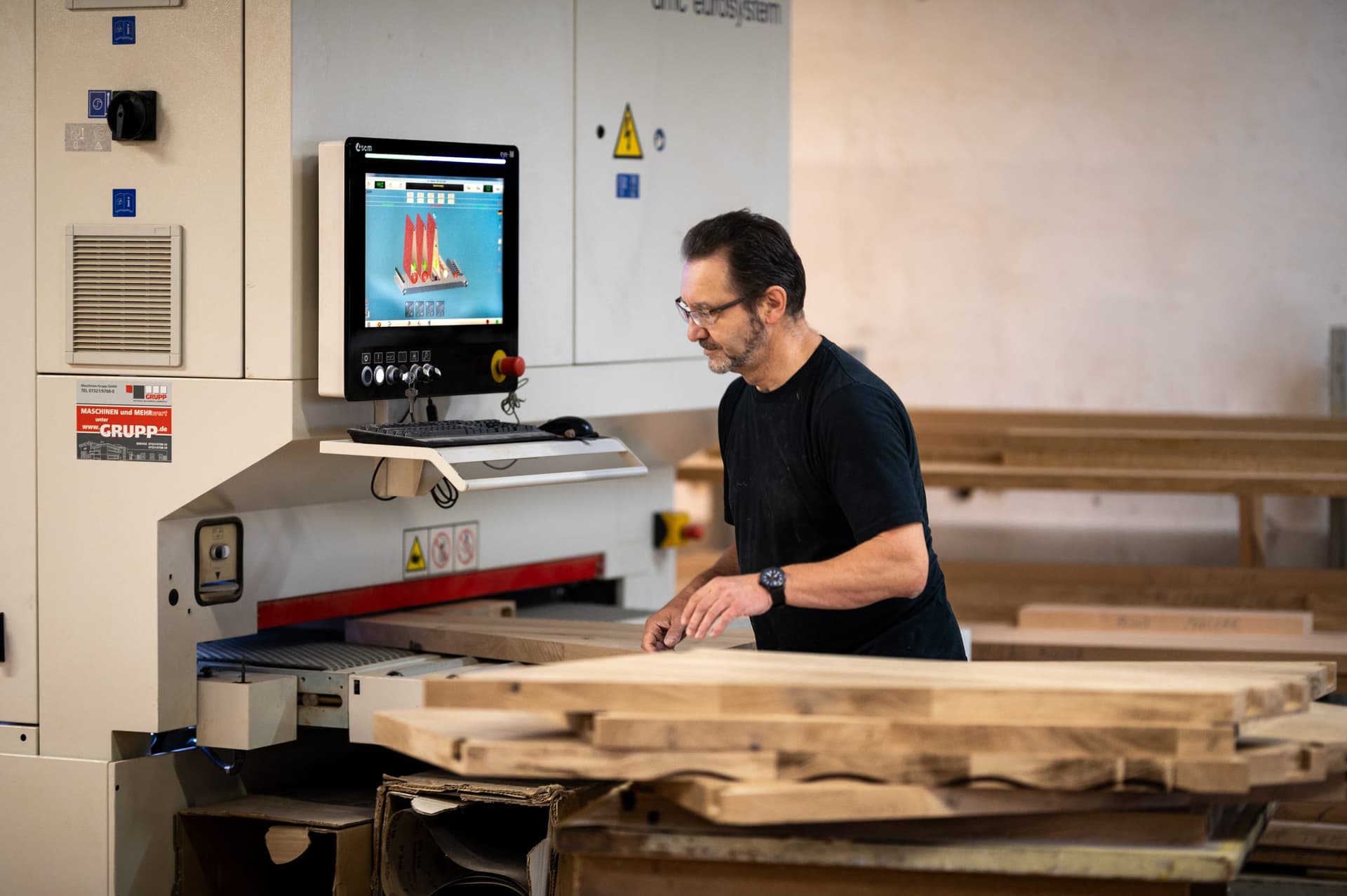 Un menuisier engage des madriers en bois massif dans la dégauchisseuse de l'atelier de Schweighofen.