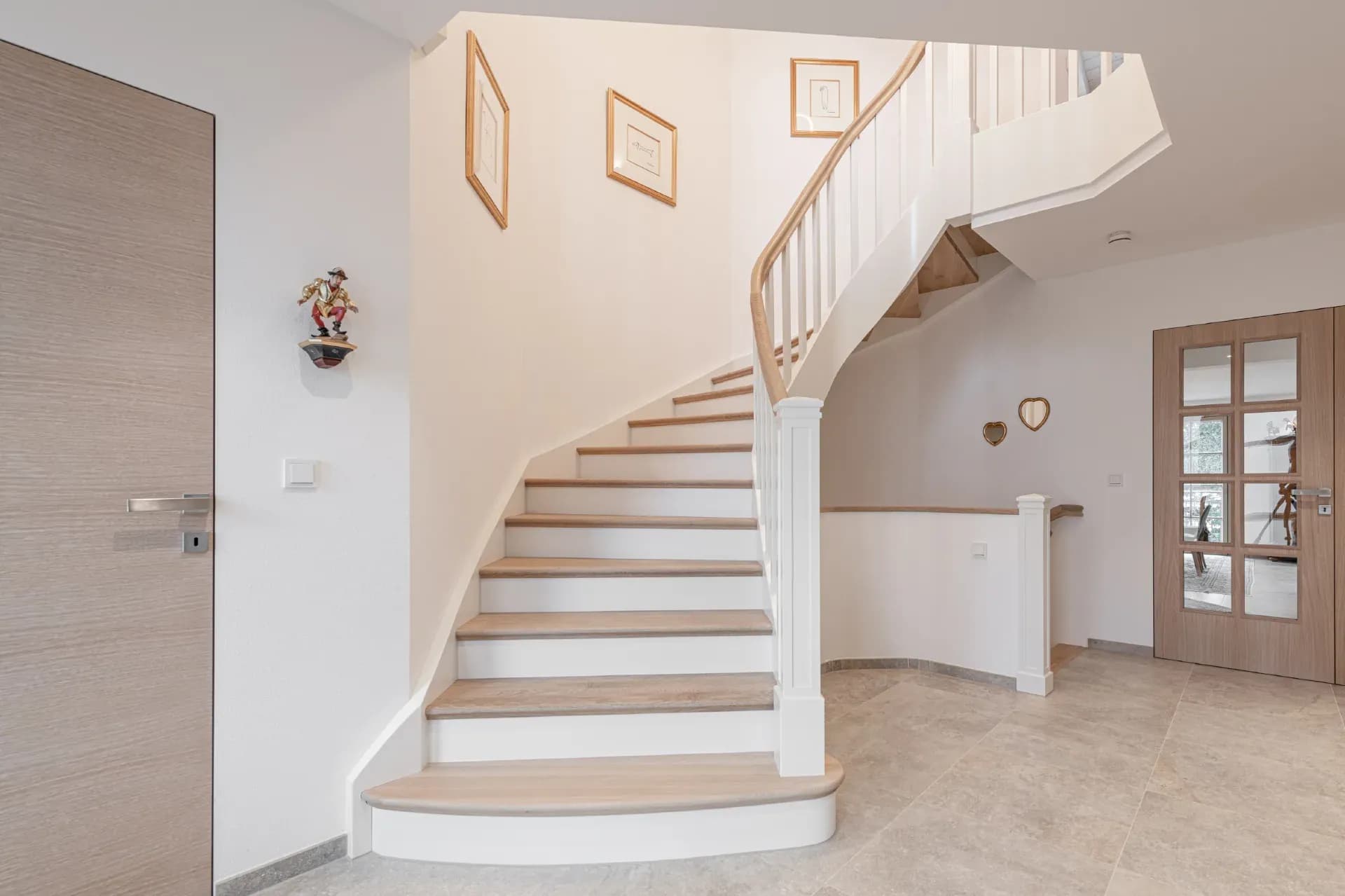 Escalier blanc de style campagne avec marches en chêne, barreaux tournés et main courante galbée dans un couloir lumineux