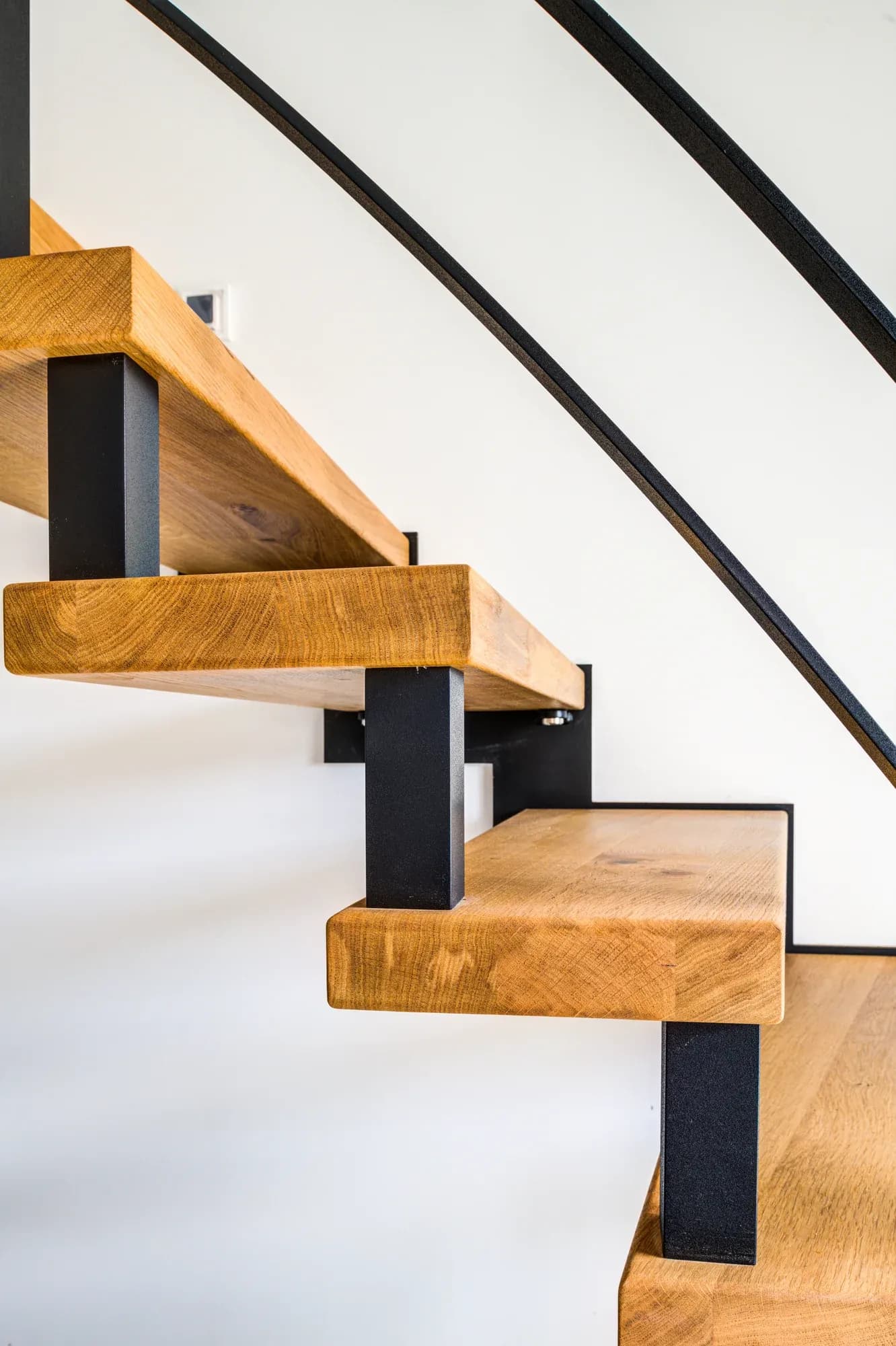 Escalier à boulons filigrane, marches en chêne et limon en acier noir, au-dessus d'un sol carrelé à motifs