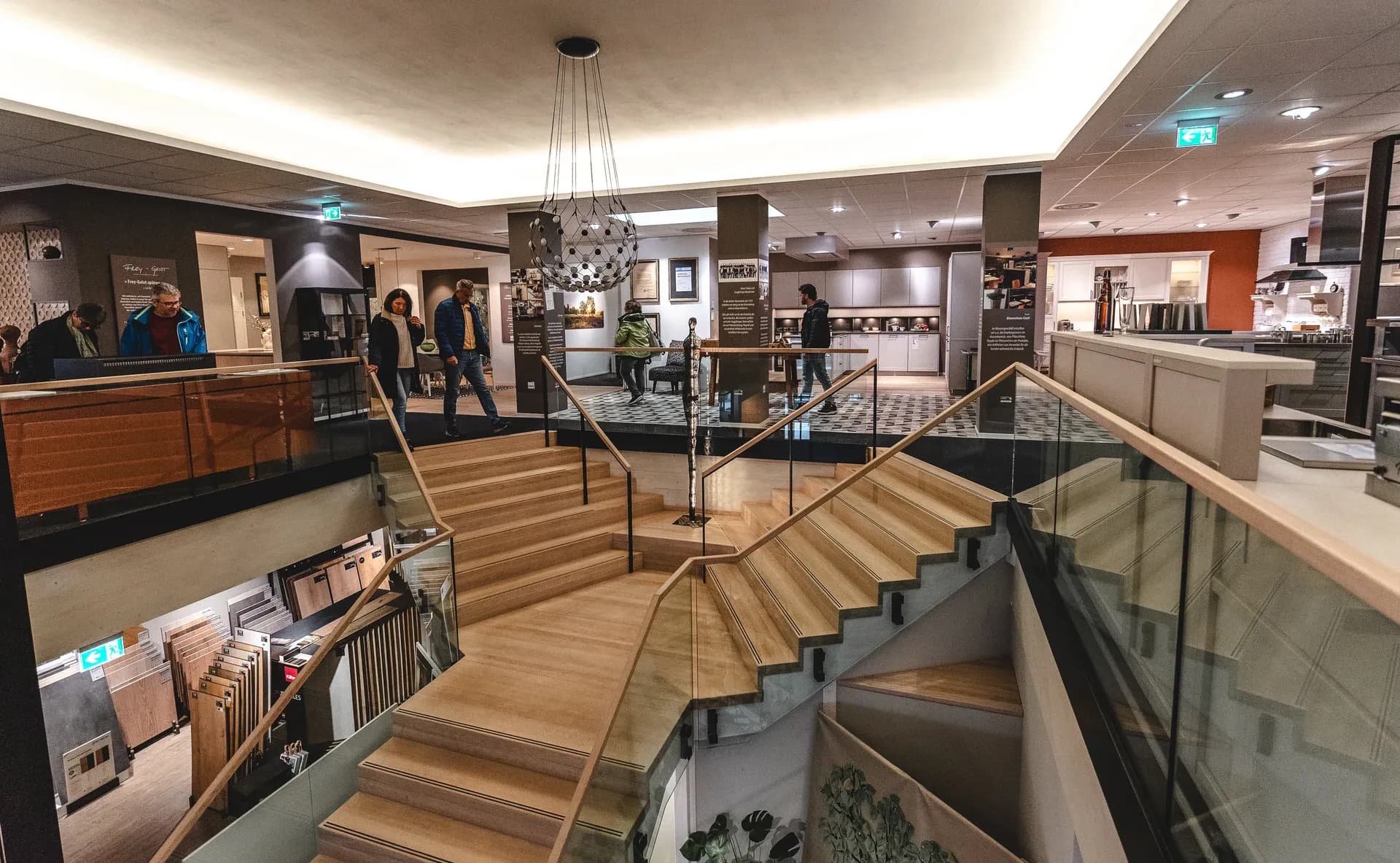 Vue du showroom Frey à Kandel : escalier en bois entre les étages, visiteurs entre les cuisines