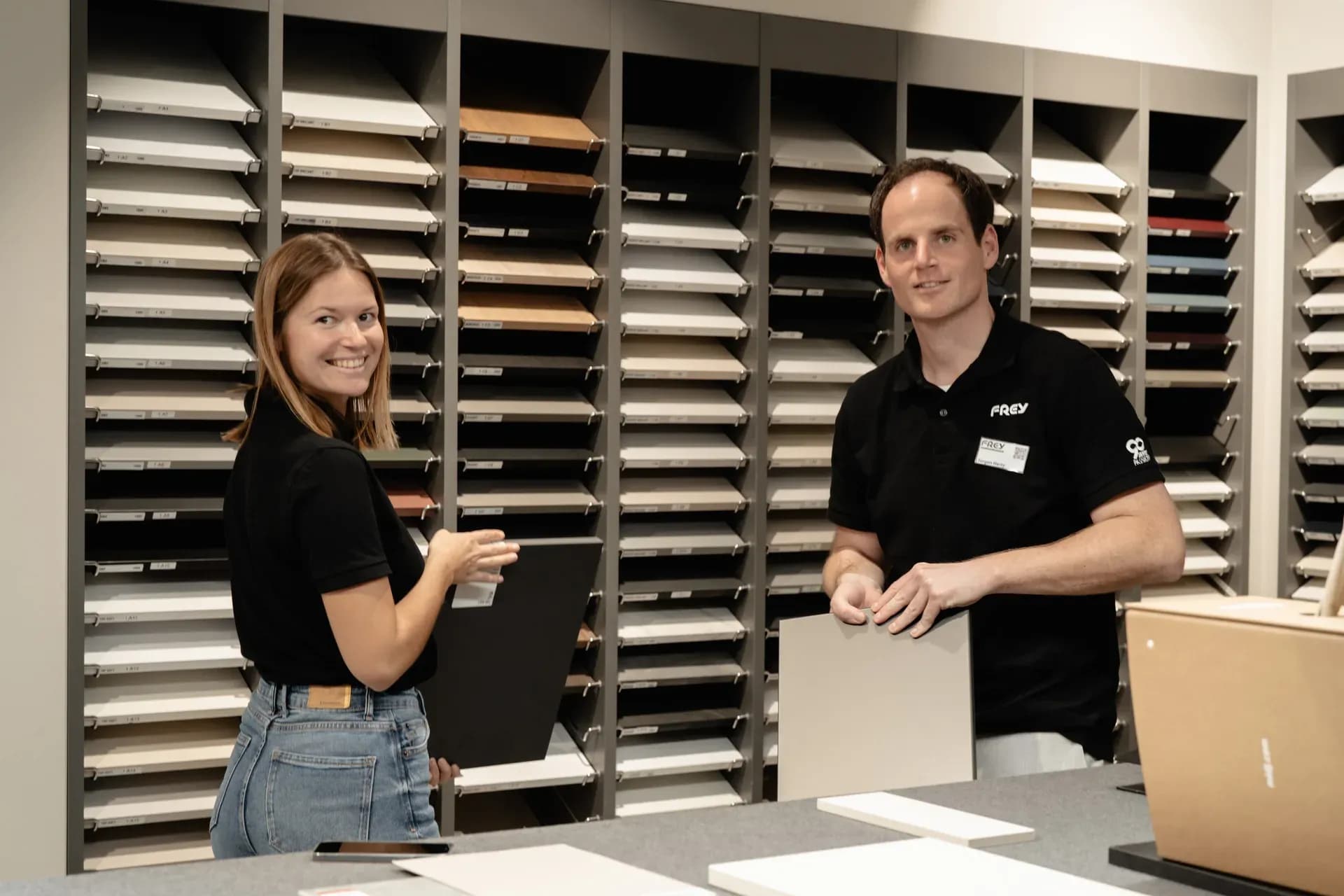 Deux conseillers Frey, échantillons de façades en main, devant le rayonnage d'échantillons du showroom de Kandel