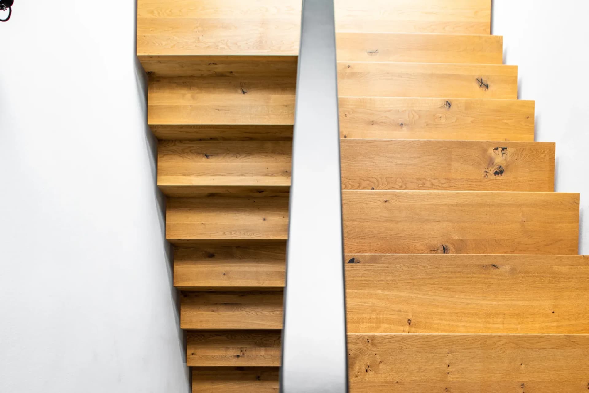 Deux volées d'un escalier en chêne noueux, séparées par un limon en acier noir.
