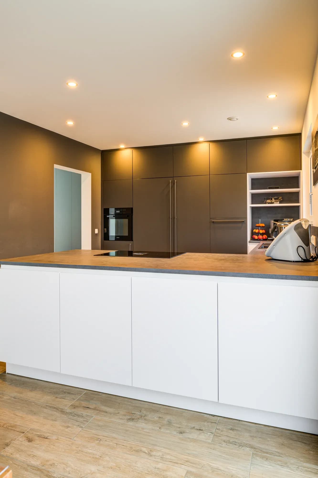 Ensemble de meubles de cuisine gris graphite avec four Miele intégré et rangée de meubles bas blancs surmontés d'un plan de travail sombre.