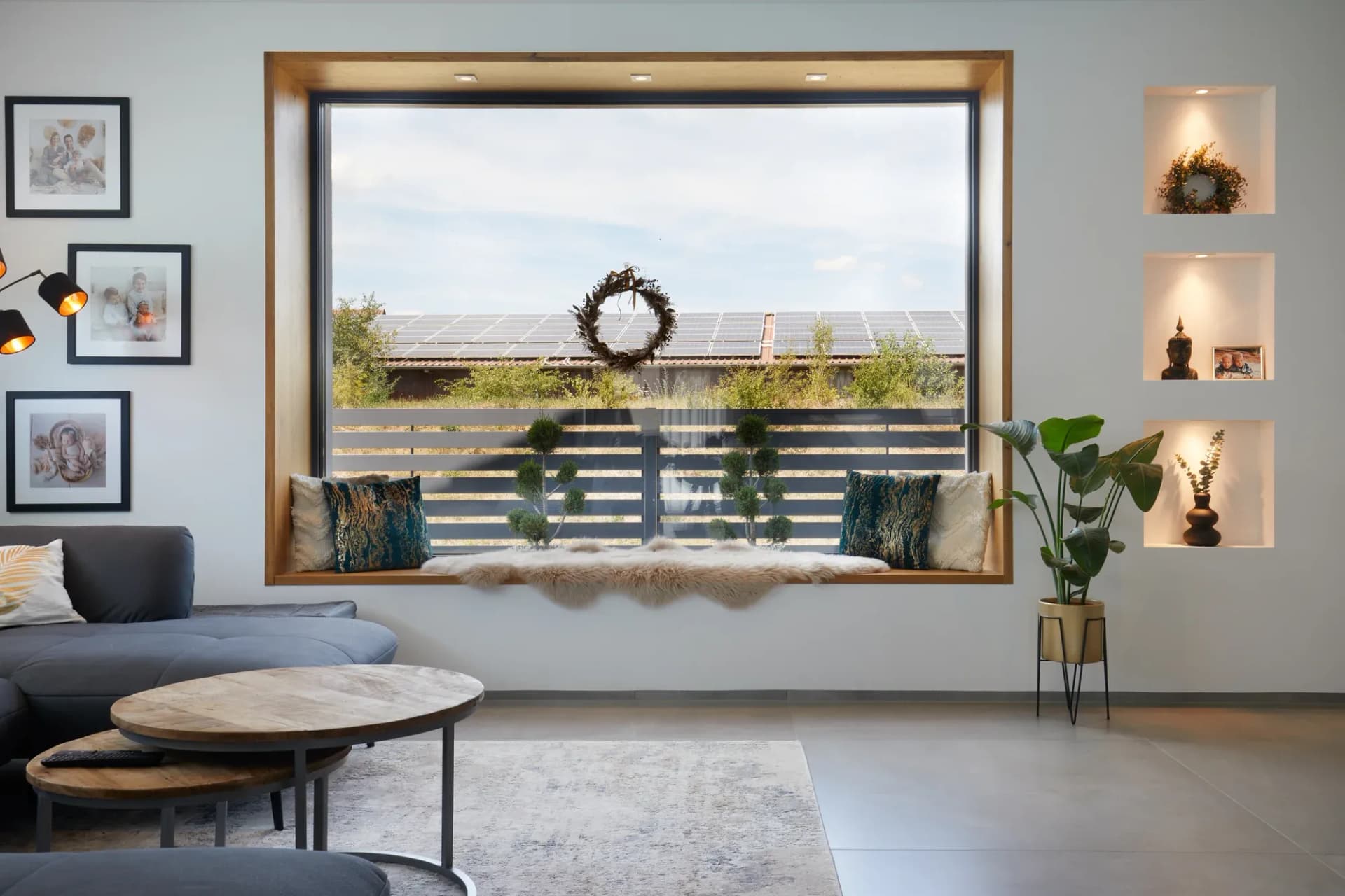 Banquette en chêne sous fenêtre avec coussins, encadrée de niches murales éclairées dans le salon