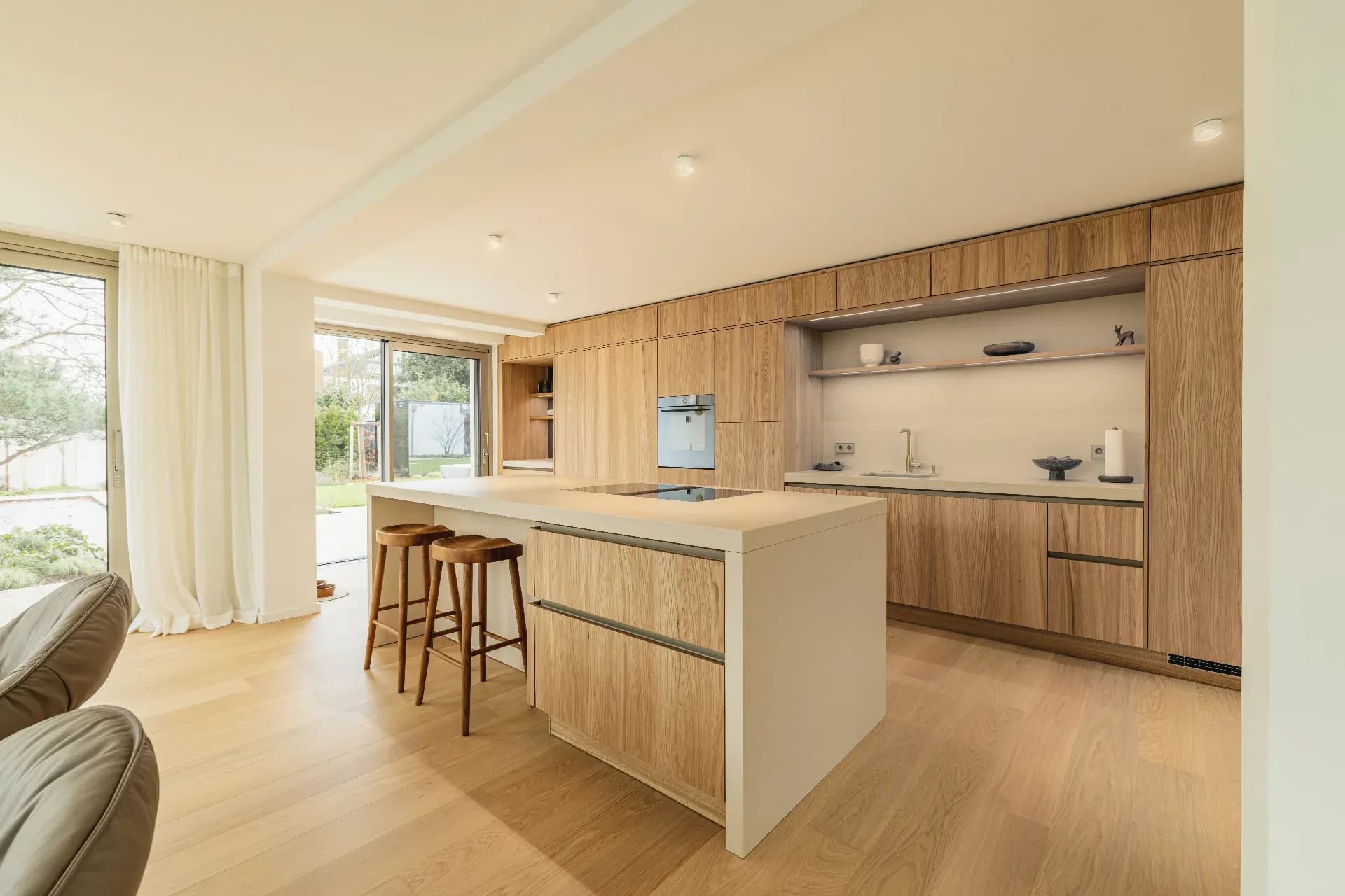 Cuisine ouverte claire avec îlot de cuisson crème et façades en placage toute hauteur