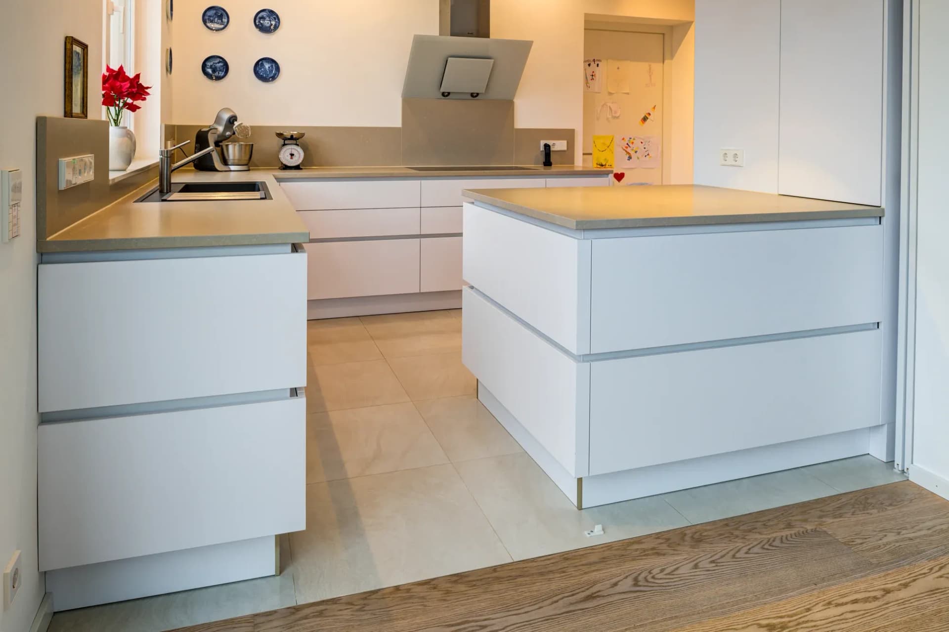 Îlot de cuisson de la cuisine blanche avec plan de travail en pierre chaleureux, assiettes décoratives bleu et blanc au mur