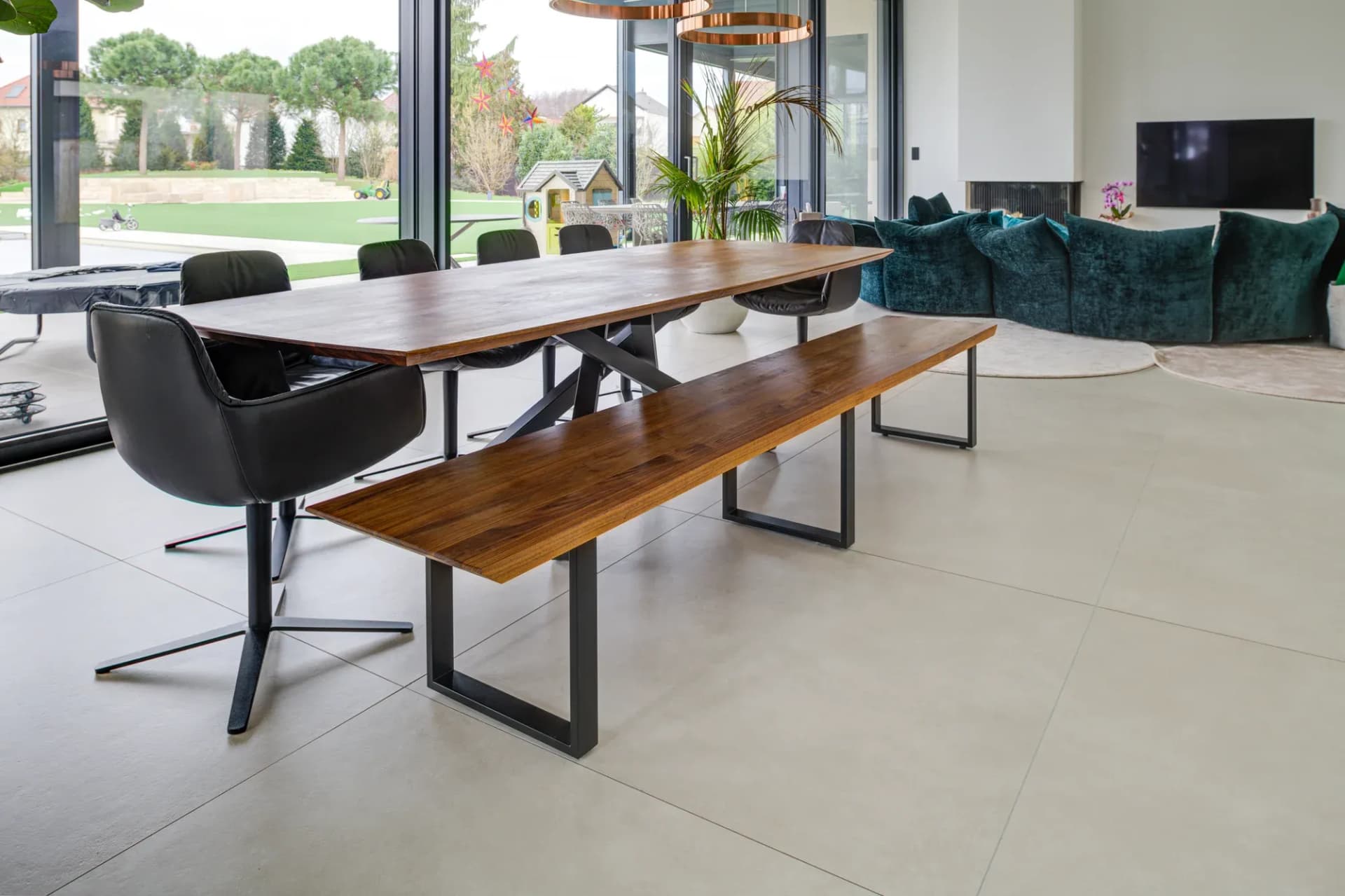 Espace repas et séjour avec panneau en bois, banquette, vitrage toute hauteur et canapé vert