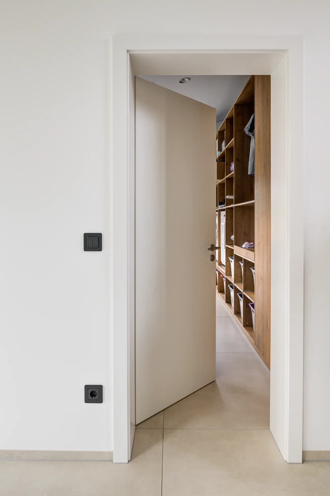 Porte sans poignée ouverte laissant apparaître un dressing en bois de chêne