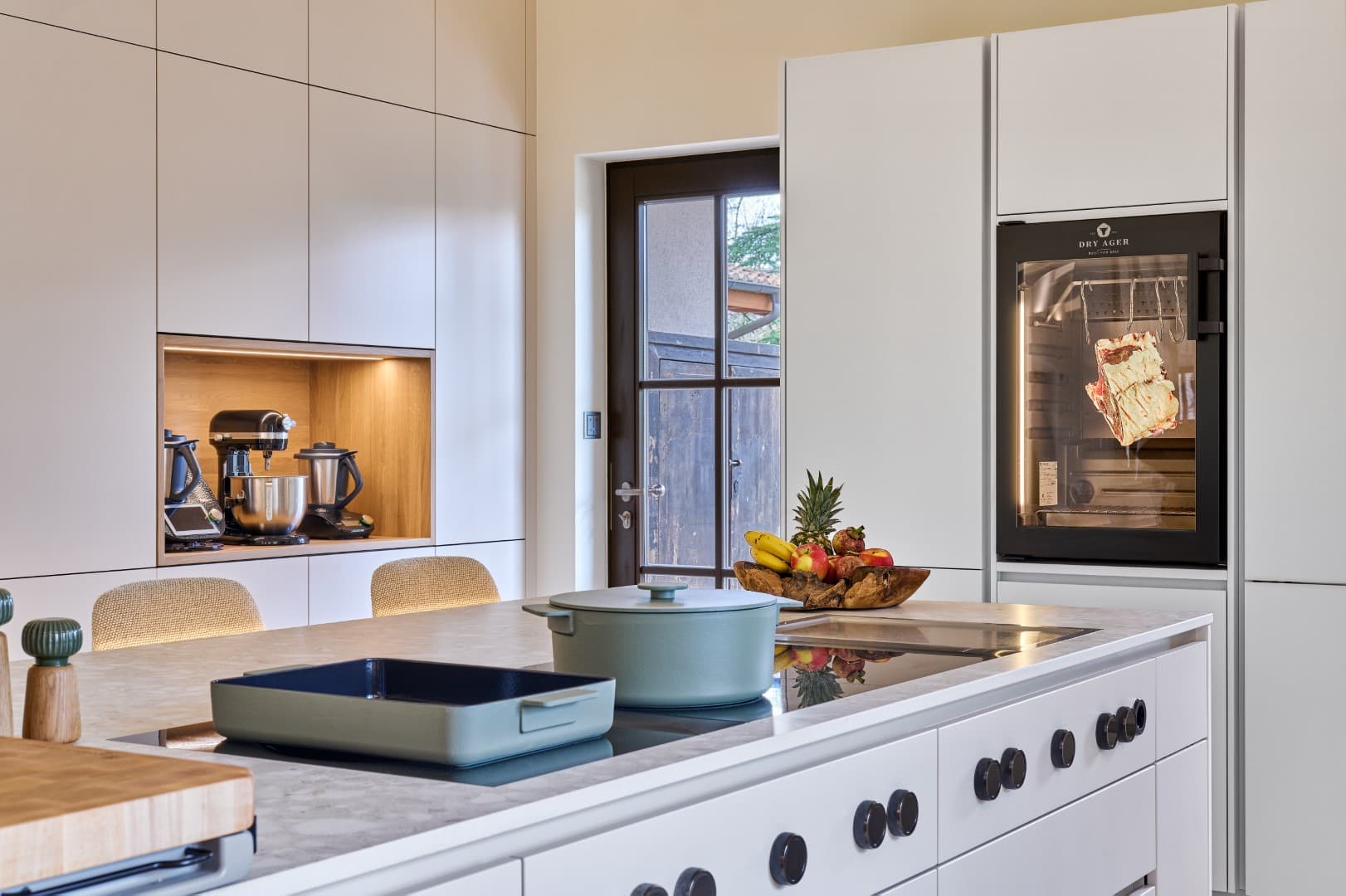 Le plan de travail de la cuisine avec table de cuisson à aspiration BORA Professional et grill en acier inoxydable Tepan intégré, encadré de meubles et d'étagères modernes