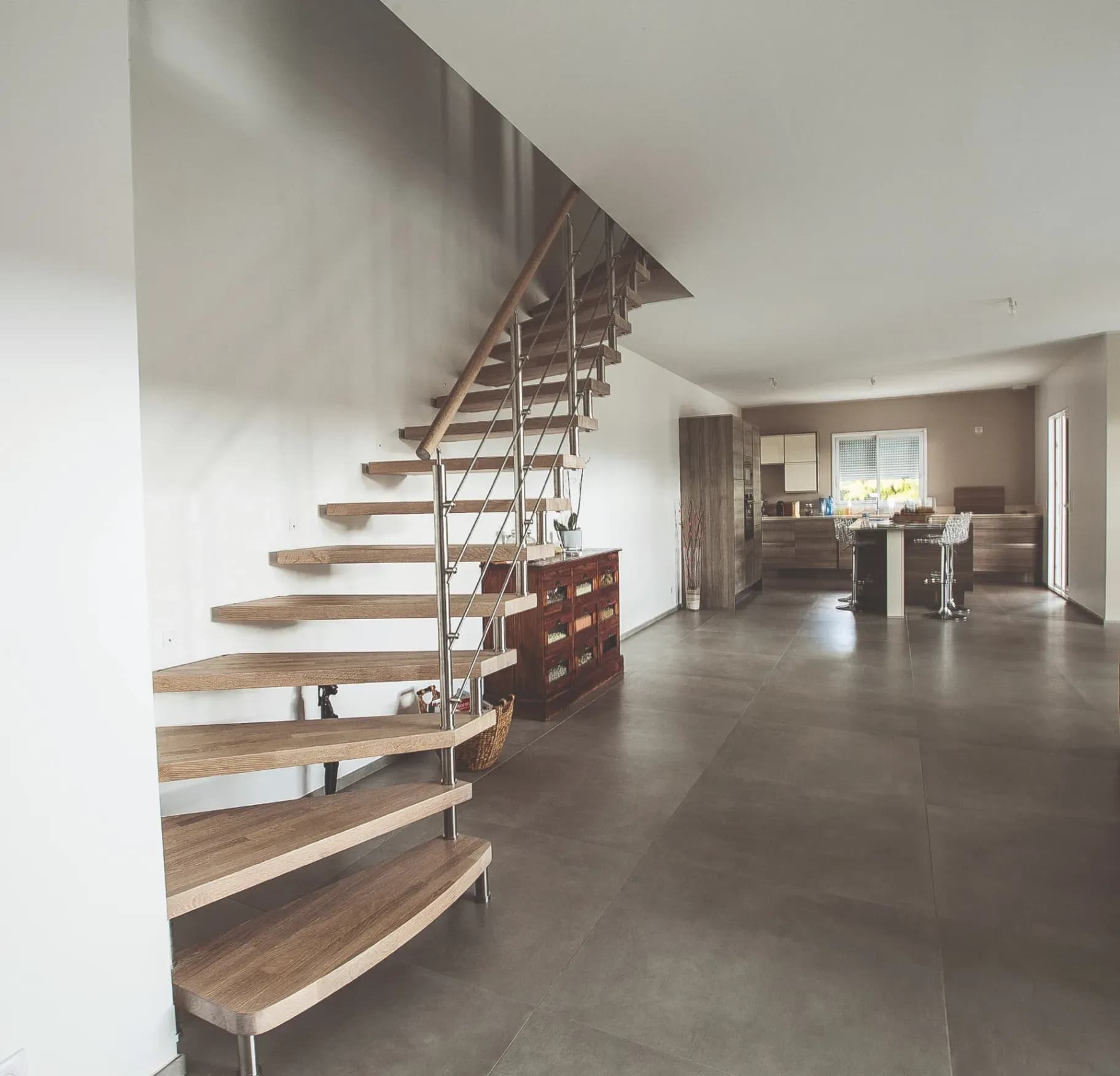 Escalier à boulons demi-tournant avec marches en chêne et barreaux en acier inoxydable dans un séjour ouvert
