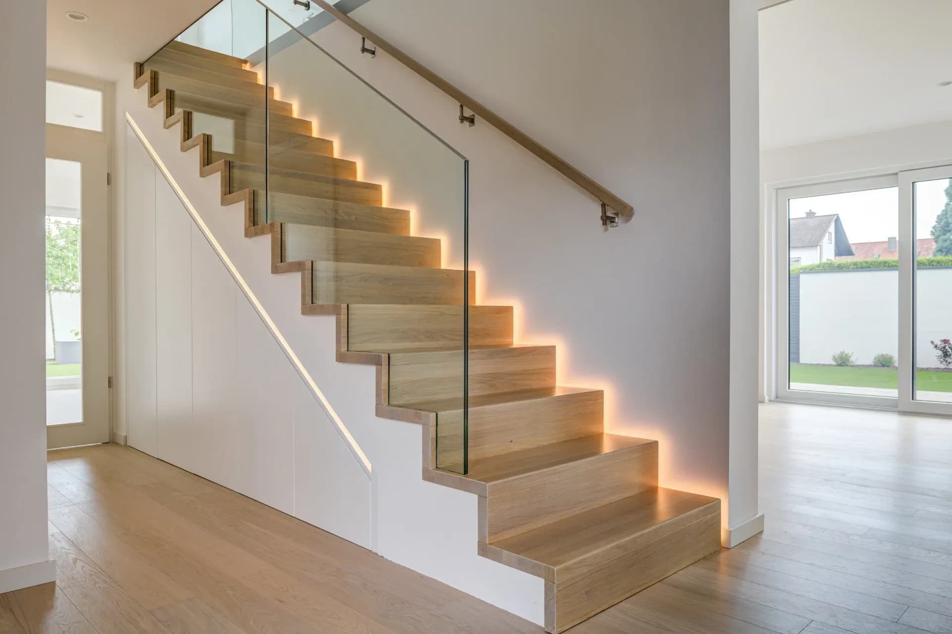 Escalier plié en chêne avec garde-corps en verre, marches éclairées et placards intégrés sur mesure en dessous