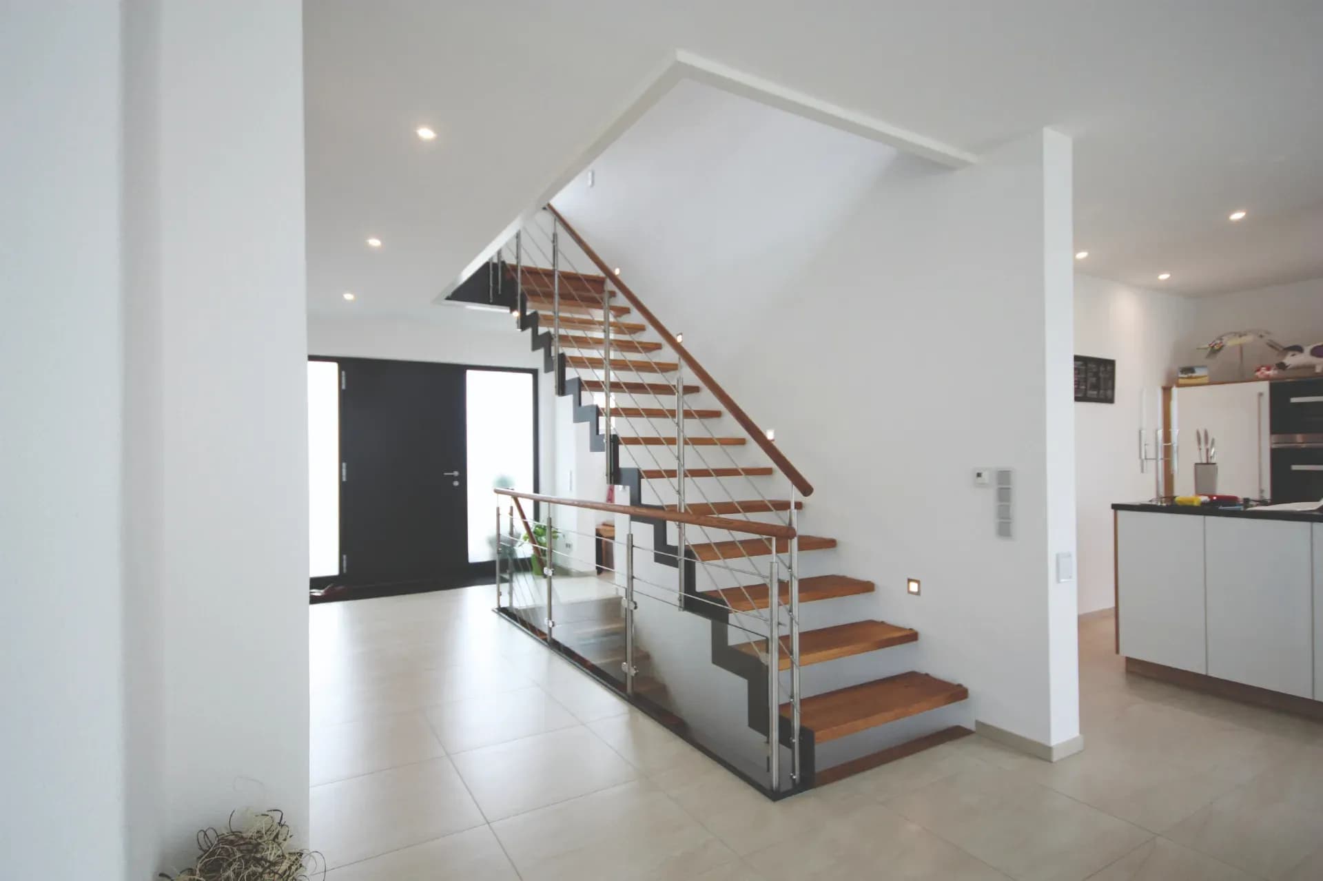 Escalier à limon à crémaillère en acier, marches en bois et garde-corps en acier inoxydable, entre le couloir et la cuisine ouverte