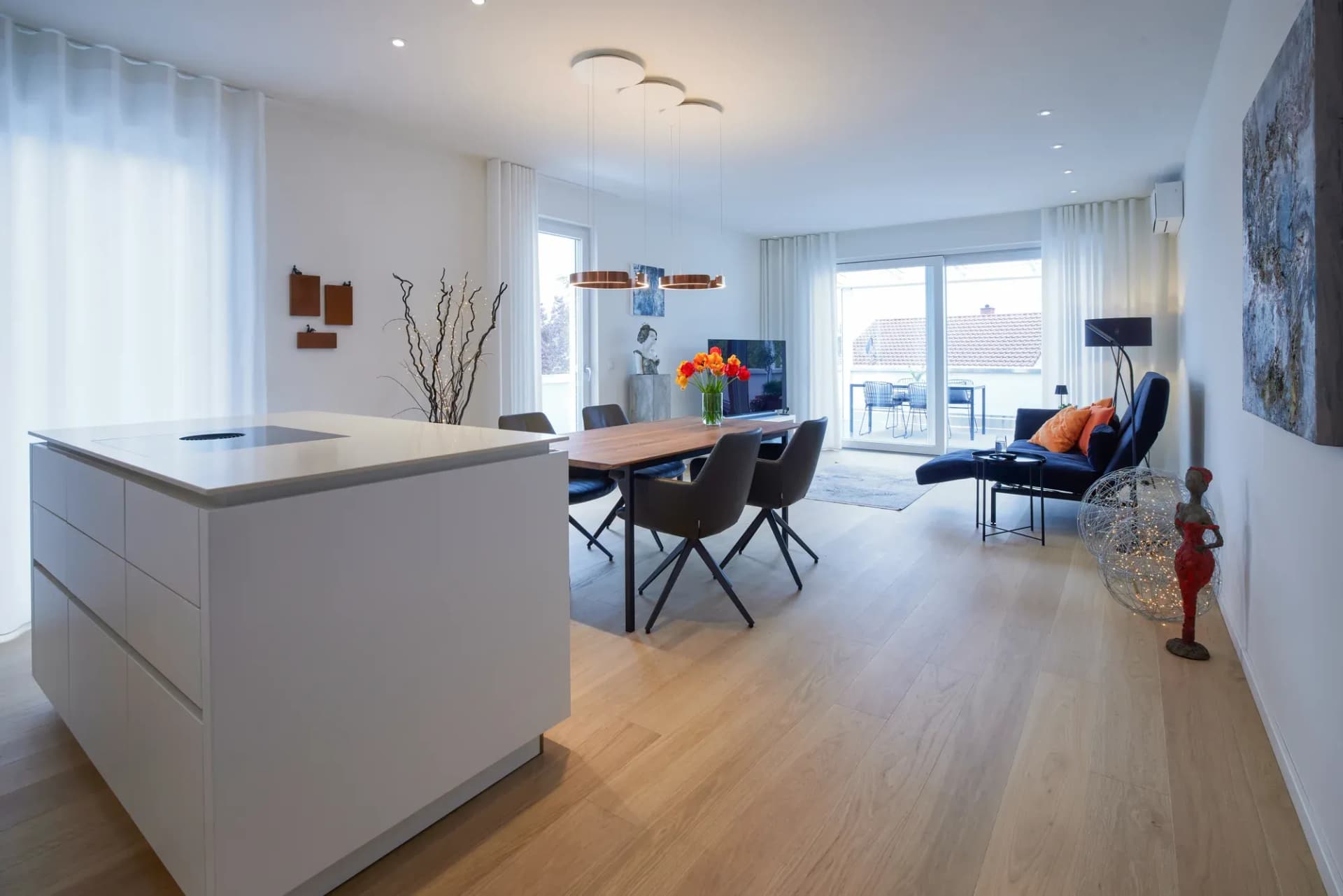 Vue sur le coin repas et le séjour avec parquet en chêne style maison de campagne se prolongeant jusqu'à la baie vitrée toute hauteur.