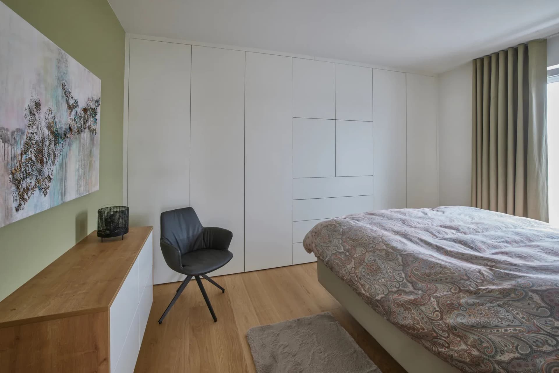 Chambre à coucher avec armoire murale intégrée blanche et console flottante en chêne le long du mur.
